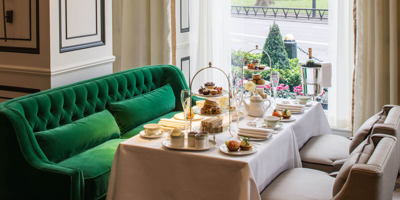 Full Afternoon Tea set up with plush green velvet sofa behind
