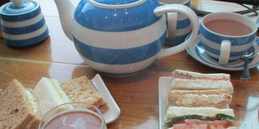 blue and white stripy tea pot, cup of tea and selection of finger sandwiches
