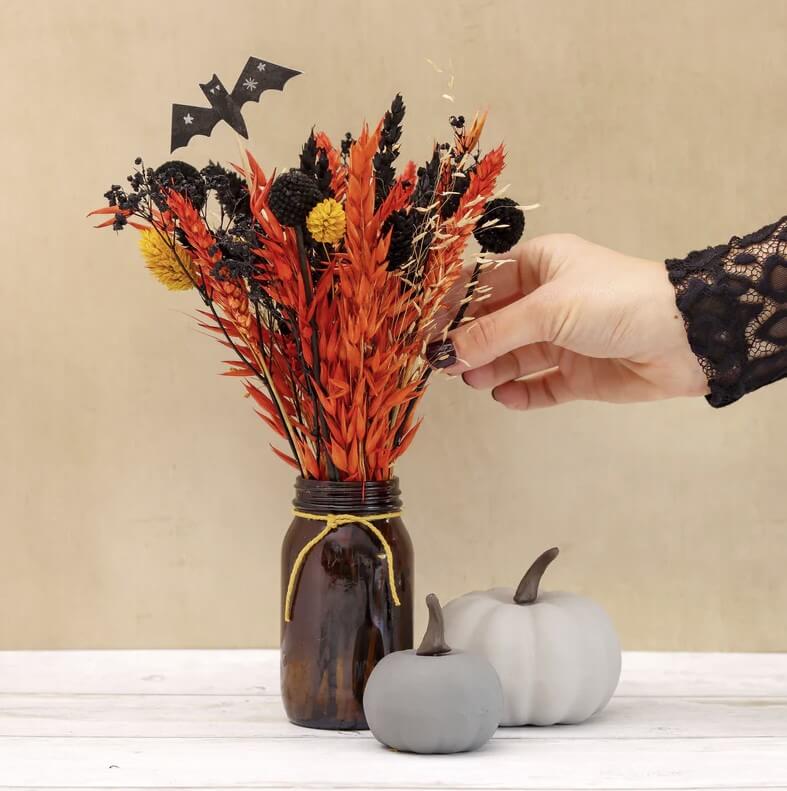 dried halloween themed flowers in orange, yellow, black with a paper bat