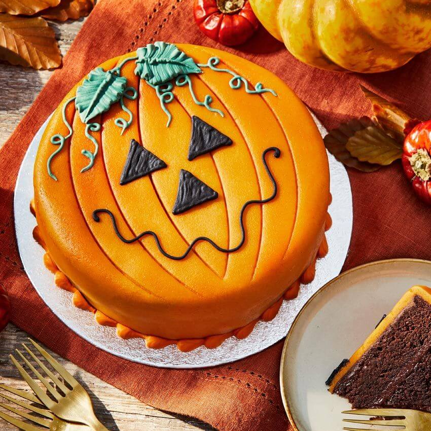 orange pumpkin cake with green leaves and halloweeny 'carving'
